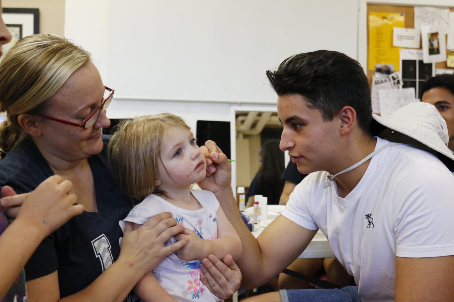 Christen Rowland watches as Carlos Flores (class of 2018) paints her daughter's face at the 2017 Arts Festival in this file photo.